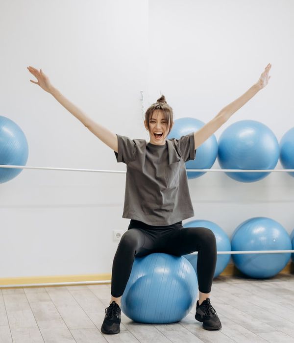 Woman smiling peacefully during a light stretching exercise in a bright room.